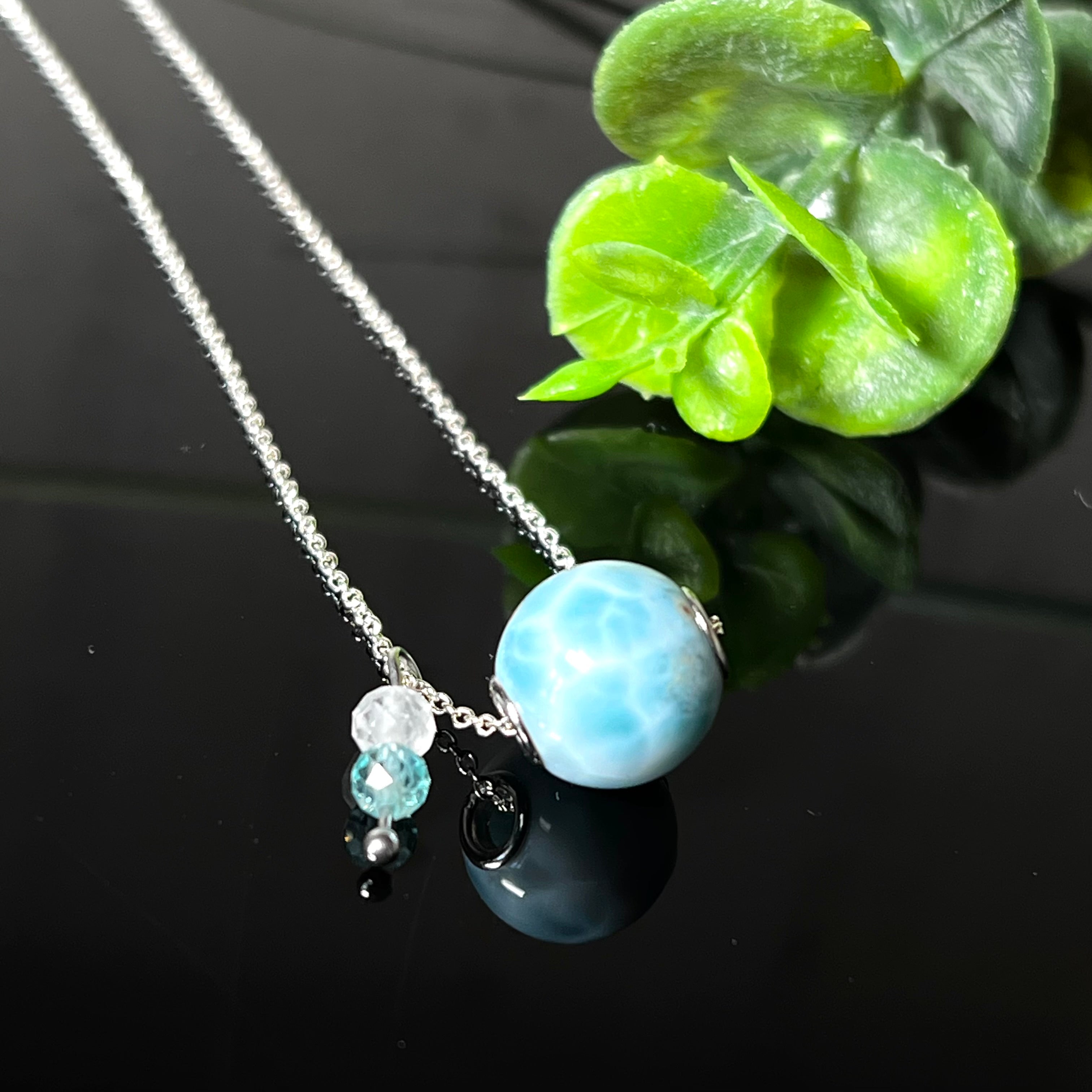 Feine Halskette aus 925er Silber mit einer polierten Larimar-Perle als Hauptstein, ergänzt durch funkelnde Apatit- und Bergkristall-Perlen. Der Edelstein mit seiner typischen Meeresfärbung erinnert an tropische Lagunen und steht für innere Ruhe und Klarheit.Ideal als Geschenk zum Geburtstag, für Meerliebhaber oder spirituelle Schmuckträgerinnen.
