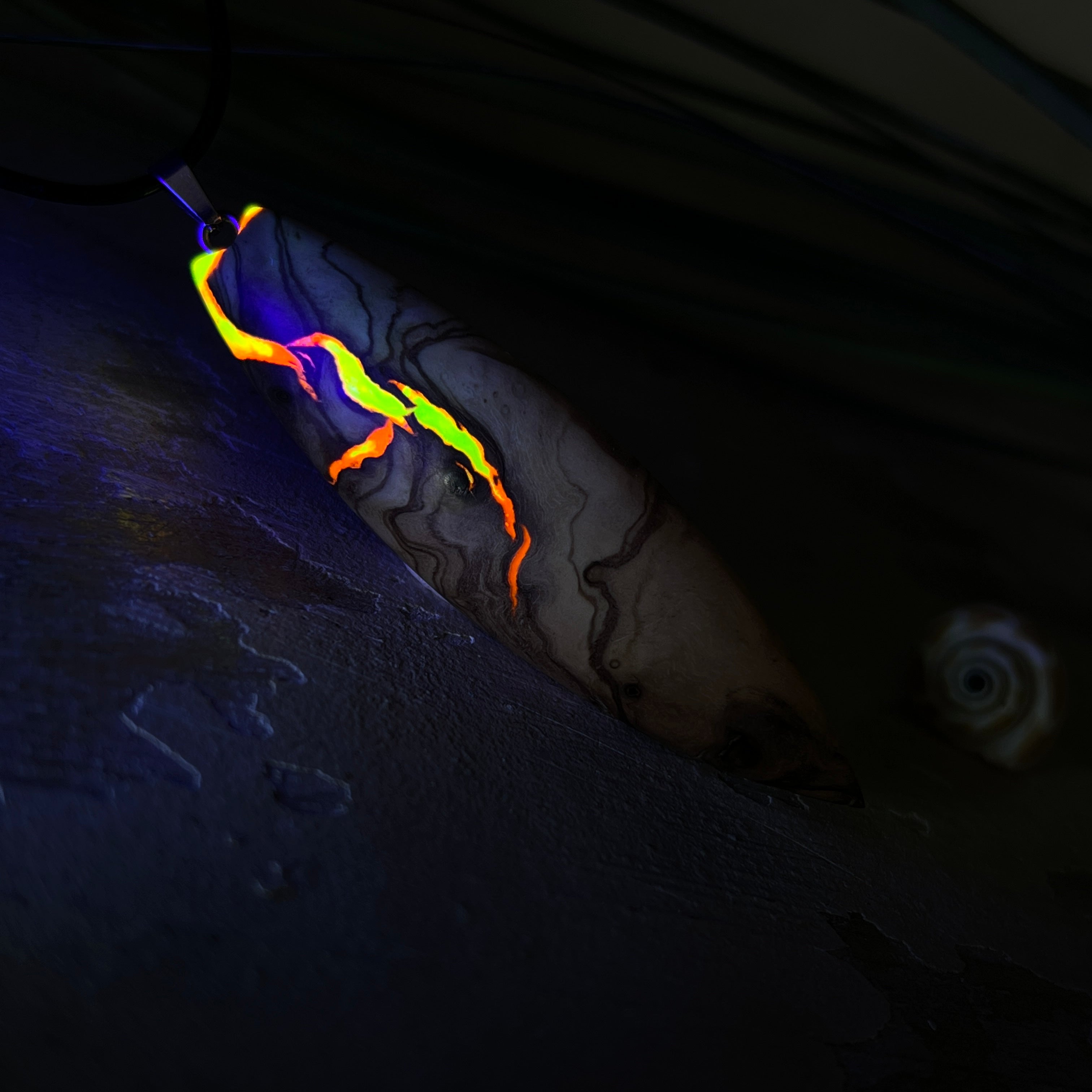 Handgefertigter Surfbrett-Anhänger aus Olivenholz und fluoreszierendem Harz in Gelb und Orange. Das leuchtende Harz beginnt unter Schwarzlicht intensiv zu strahlen und macht den Anhänger zu einem echten Highlight. Größe ca. 6,3 × 2 cm, mit Edelstahl-Anhängerschlaufe und Lederkette mit Edelstahlverschluss und 5 cm Verlängerung. Jedes Schmuckstück ist ein Unikat – Maserung und Farbspiel sind einzigartig. Ideal für Naturliebhaber und Individualisten.