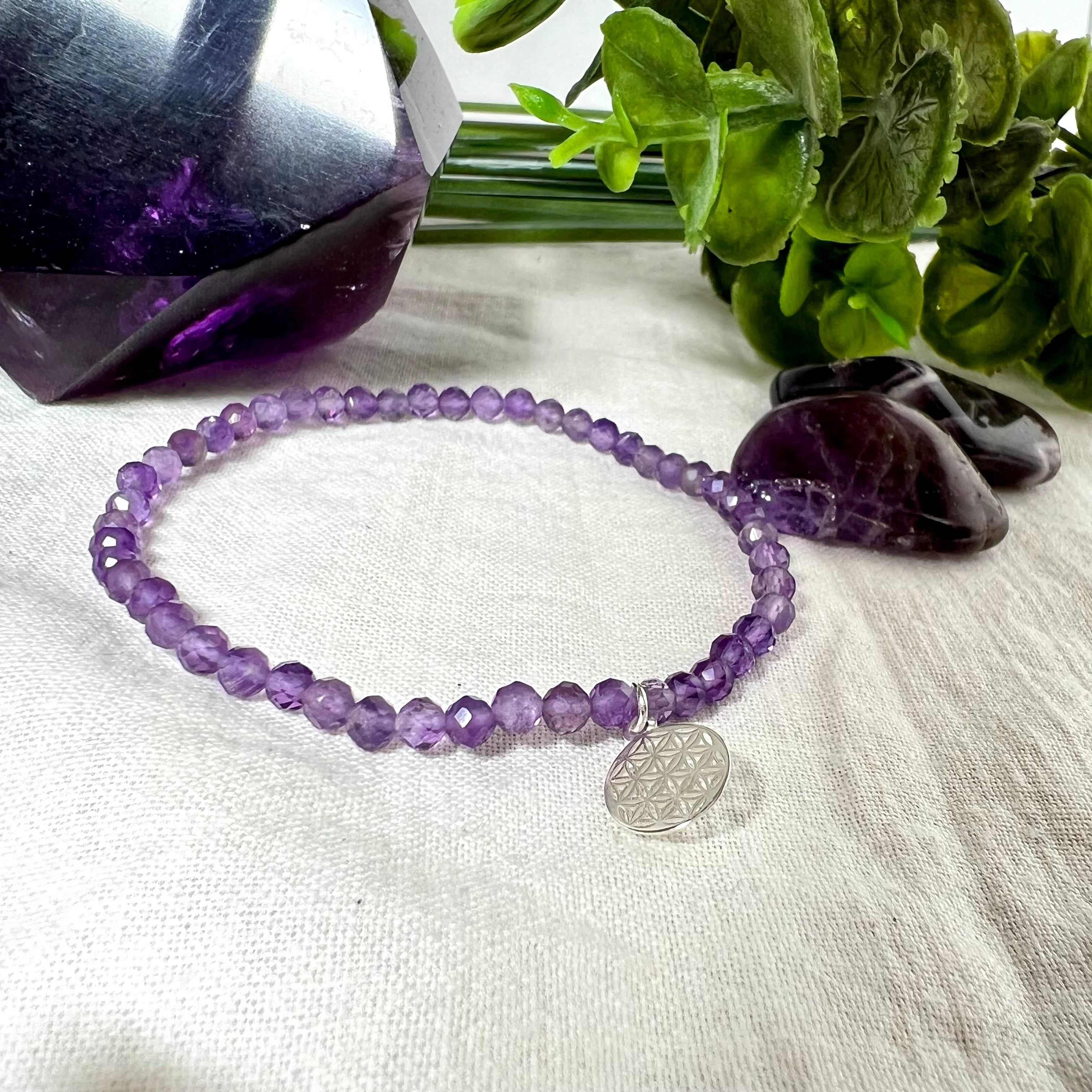 Handgefertigtes Amethyst-Armband aus facettierten 4 mm Edelstein-Perlen mit 925er Silber Charm „Blume des Lebens“. Spirituelles Schmuckstück in zartem Violett. Auf elastischem Gummiband, ca. 17 cm Innendurchmesser. Edles, fein gearbeitetes Design – ideal als Geschenk oder zur eigenen spirituellen Unterstützung.