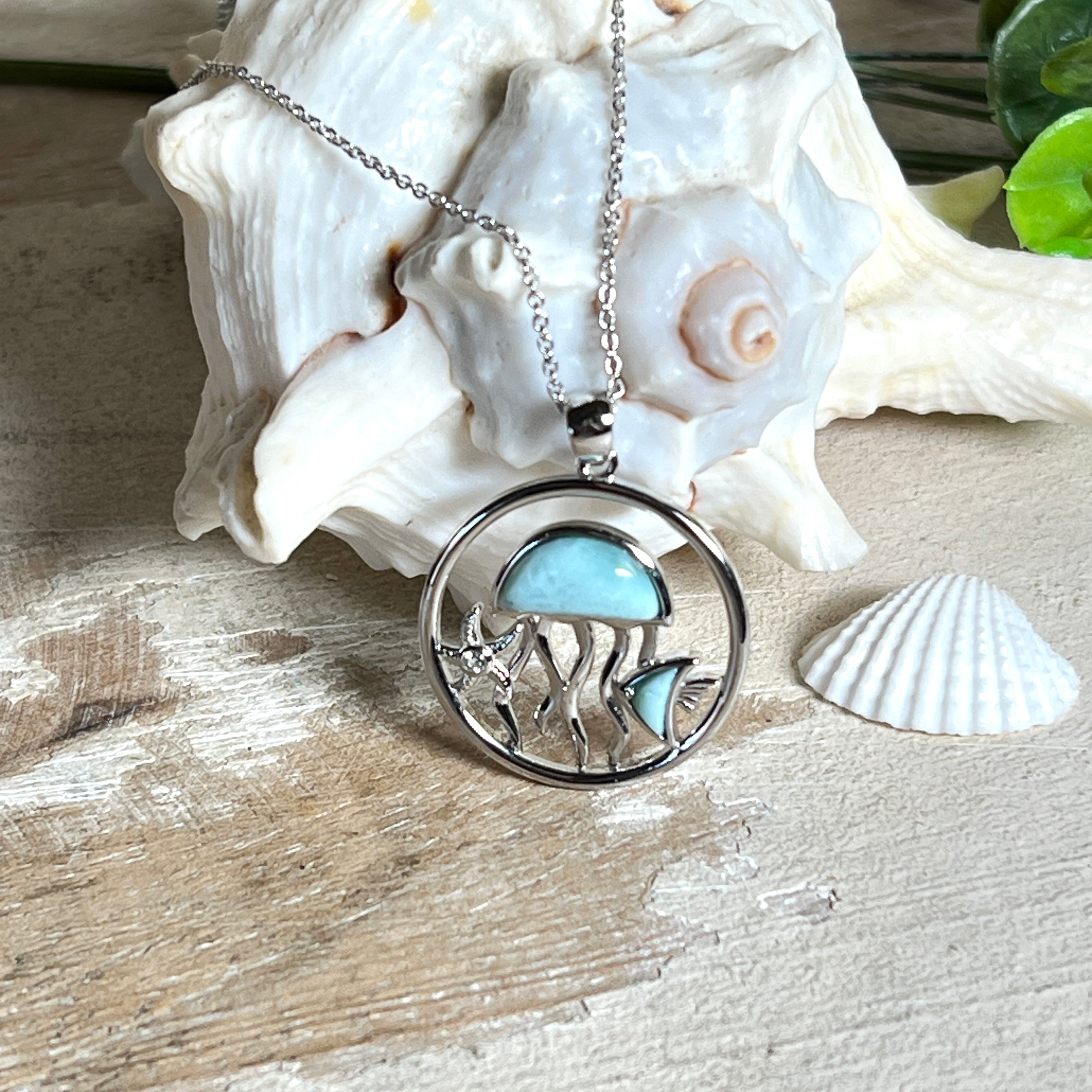 „Sealife“ – runder Anhänger aus rhodiniertem 925 Sterling Silber mit seltenem Larimar und funkelndem Topas. Das maritime Design zeigt eine Qualle, einen Fisch und einen Seestern. Anhängergröße ca. 32 × 26 mm, inklusive 45 cm langer Silberkette (1 mm Stärke). Symbol für die Schönheit und Vielfalt des Ozeans – jedes Stück ein Unikat durch das natürliche Farbspiel des Larimars.