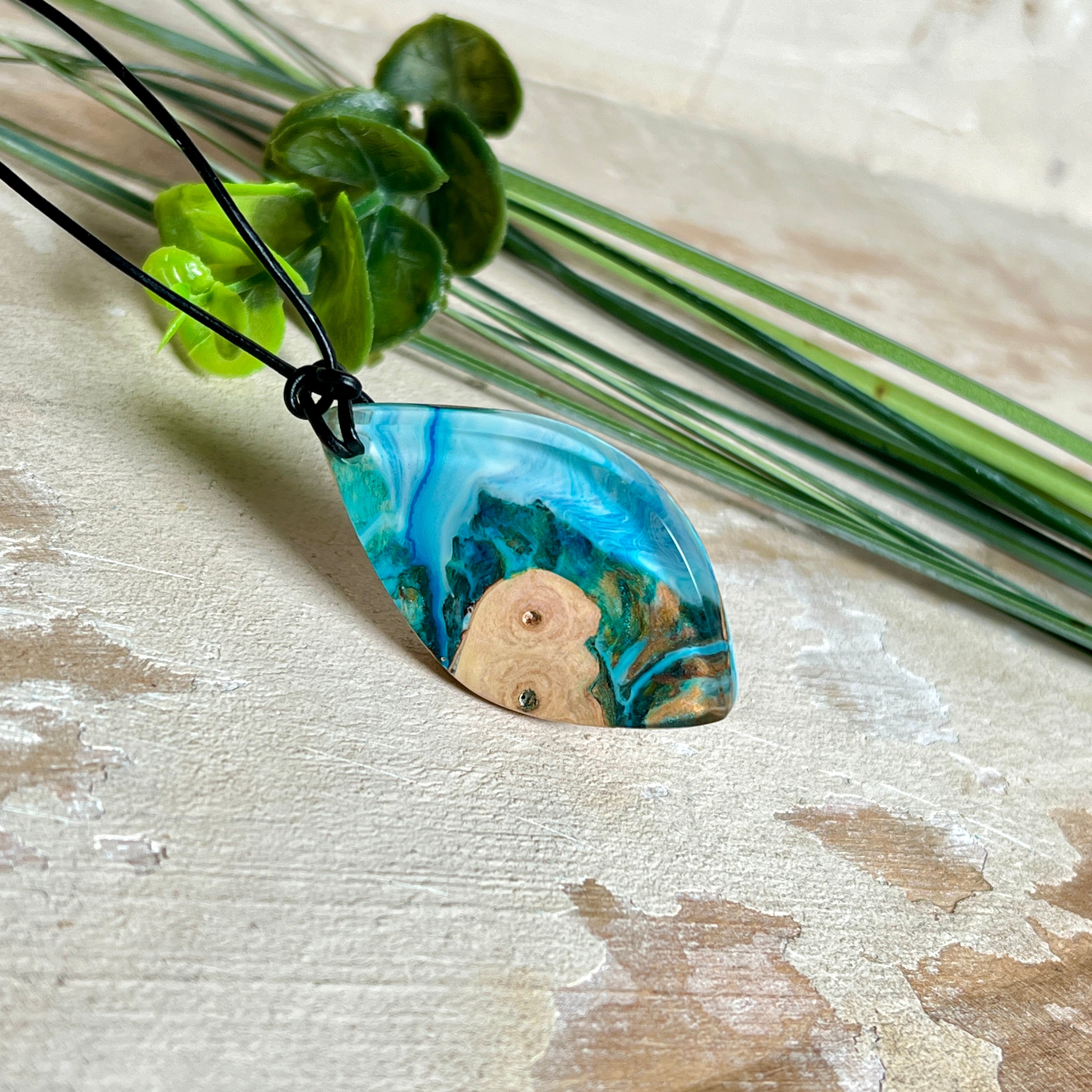 Handgefertigter Anhänger „Ocean Leaf“ aus Maserholz und Epoxidharz in Blau- und Türkistönen. Ein einzigartiges Schmuckstück, das die Schönheit von Natur und Meer einfängt. Mit verstellbarem Lederband (24–43 cm). Jeder Anhänger ist ein Unikat mit einzigartiger Maserung und Farbverlauf.