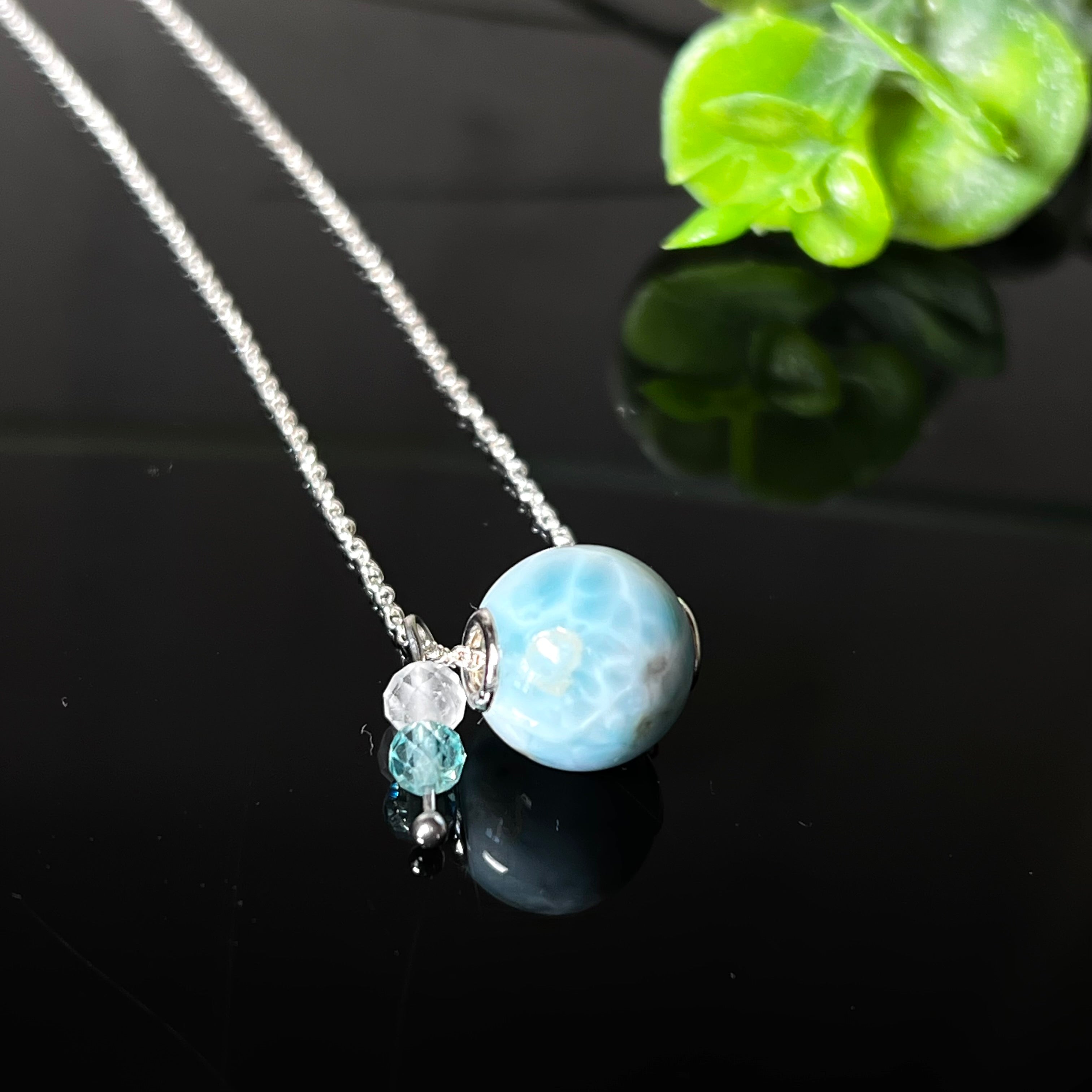 Feine Halskette aus 925er Silber mit einer polierten Larimar-Perle als Hauptstein, ergänzt durch funkelnde Apatit- und Bergkristall-Perlen. Der Edelstein mit seiner typischen Meeresfärbung erinnert an tropische Lagunen und steht für innere Ruhe und Klarheit.Ideal als Geschenk zum Geburtstag, für Meerliebhaber oder spirituelle Schmuckträgerinnen.