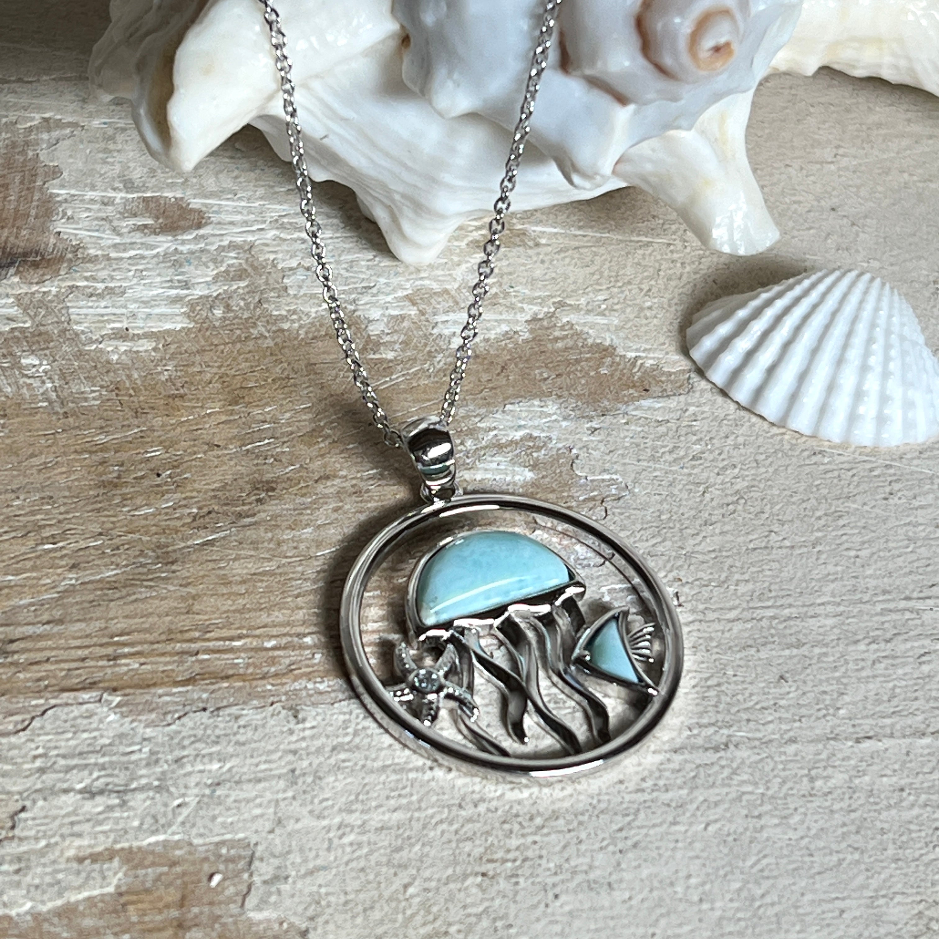 „Sealife“ – runder Anhänger aus rhodiniertem 925 Sterling Silber mit seltenem Larimar und funkelndem Topas. Das maritime Design zeigt eine Qualle, einen Fisch und einen Seestern. Anhängergröße ca. 32 × 26 mm, inklusive 45 cm langer Silberkette (1 mm Stärke). Symbol für die Schönheit und Vielfalt des Ozeans – jedes Stück ein Unikat durch das natürliche Farbspiel des Larimars.
