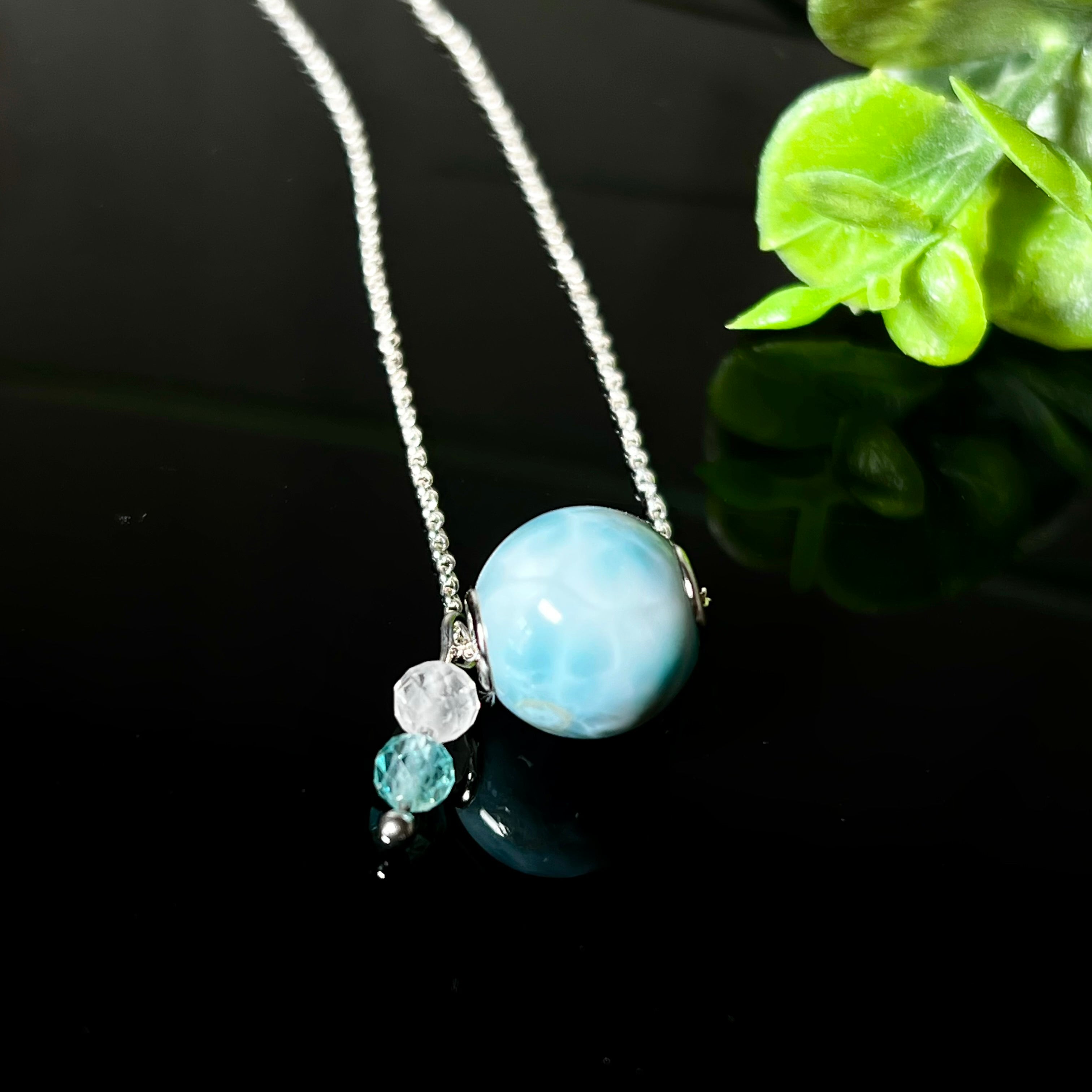 Feine Halskette aus 925er Silber mit einer polierten Larimar-Perle als Hauptstein, ergänzt durch funkelnde Apatit- und Bergkristall-Perlen. Der Edelstein mit seiner typischen Meeresfärbung erinnert an tropische Lagunen und steht für innere Ruhe und Klarheit.Ideal als Geschenk zum Geburtstag, für Meerliebhaber oder spirituelle Schmuckträgerinnen.