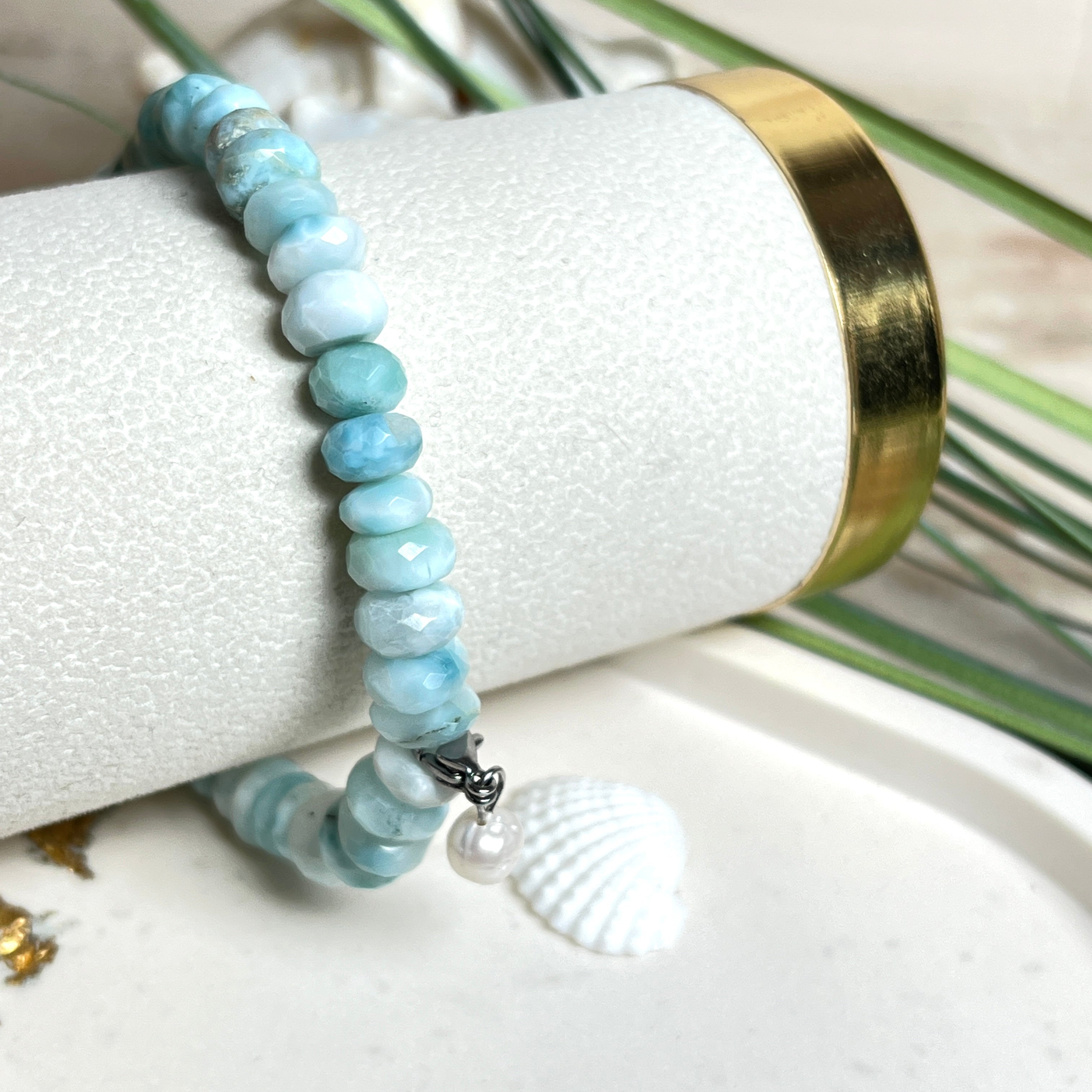 Handgefertigtes Armband aus seltenem Larimar mit facettierten, türkis-blauen Edelsteinperlen (Ø ca. 6–7 mm), elastischem Band und einem zarten Süßwasserperlen-Charm an Edelstahlkarabiner. Der wertvolle Larimar, auch „Stein des Atlantis“ genannt, gilt als Edelstein der Ruhe und Meeresverbundenheit.