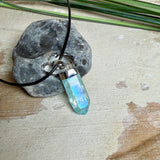 Nahaufnahme einer handgefertigten Halskette mit Aqua Aura Rohkristall: naturbelassener, sechskantiger Bergkristall mit goldbedampfter Aqua-Beschichtung in Türkisblau, gefasst in 925er Silber und getragen an einer schwarzen Lederkette mit Edelstahl-Karabiner und Verlängerungskettchen.