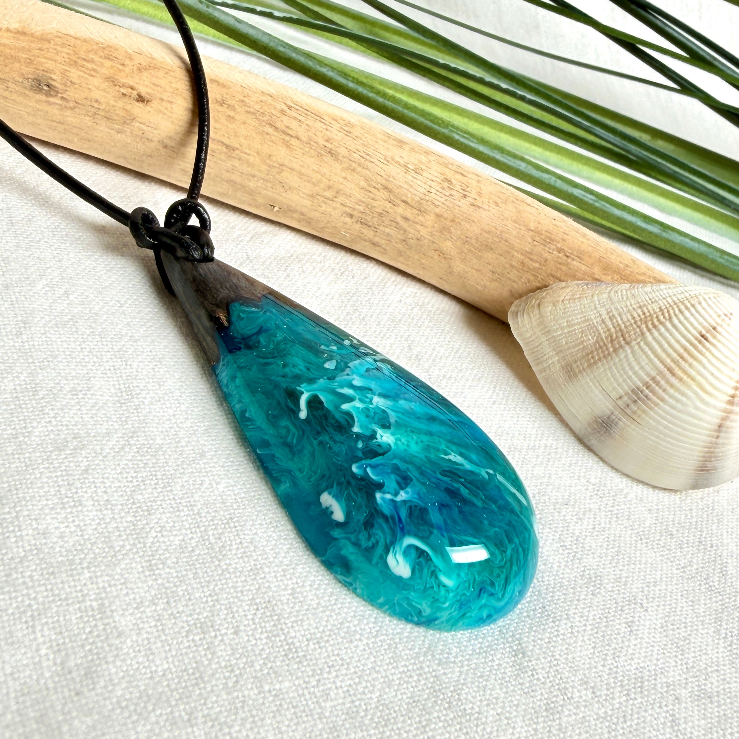 Tropfen Anhänger aus dunklem Maserholz und Epoxidharz in Türkis Blau mit weißer Wellenstruktur am schwarzen Lederband, maritimer Holz Harz Naturschmuck