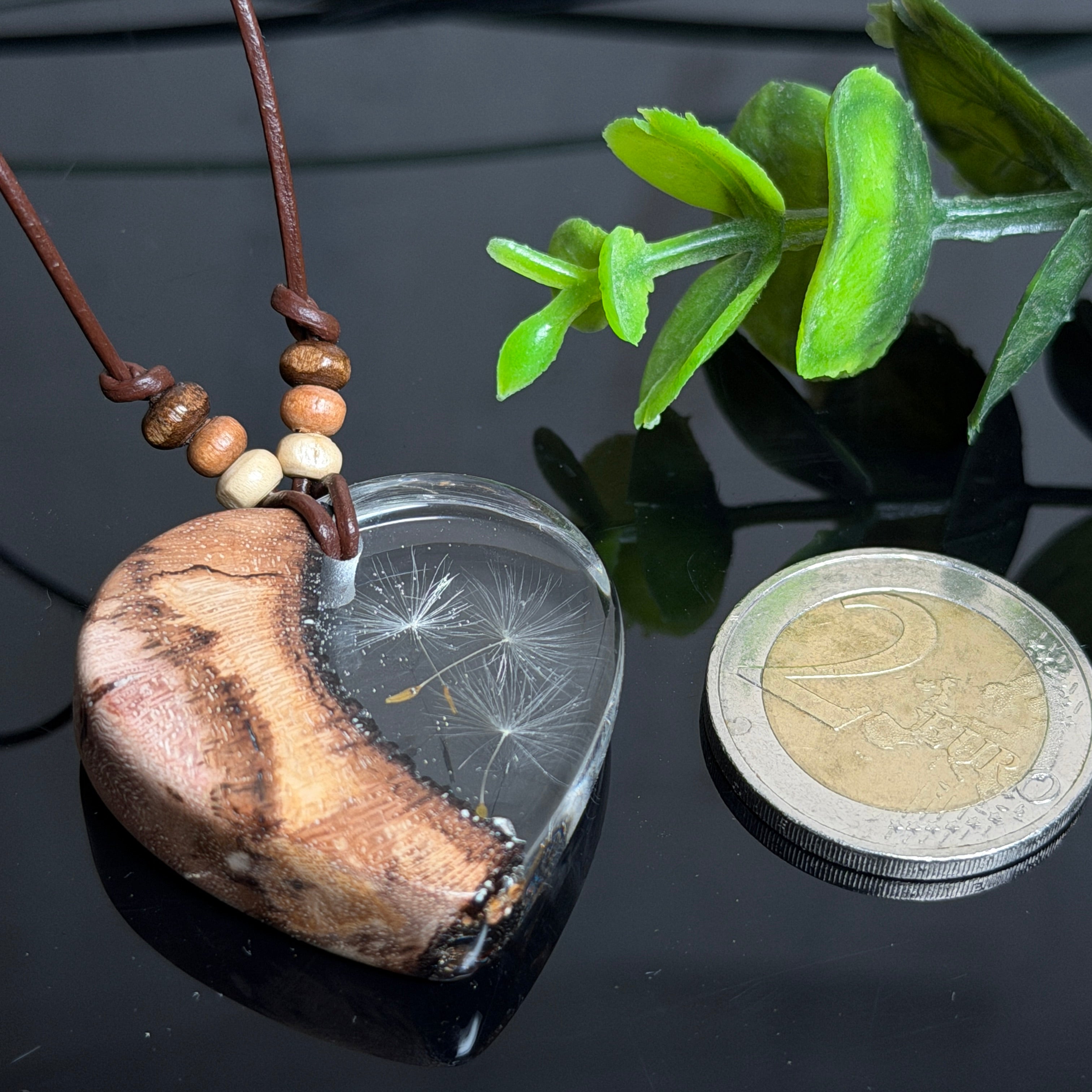 Herzanhänger „Pusteblumenzauber“ aus naturbelassenem Rebholz und klarem Epoxidharz mit schwebenden Pusteblumensamen. Dunkelbraunes, verstellbares Lederband mit kleinen Holzperlen, Anhänger ca. 3,5 × 3,5 cm. Handgefertigtes Unikat von ZeitlosSchmuckDesign.