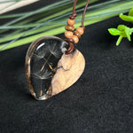 Handgefertigter Herzanhänger aus Olivenholz und klarem Harz mit echten Pusteblumen. Der Anhänger misst ca. 3,5 cm, das Lederband ist verstellbar von 23–43 cm und mit kleinen Holzperlen verziert. Ein natürliches Unikat, Symbol für Wünsche und Glück – sorgfältig gegossen, gesägt, geschliffen und poliert.