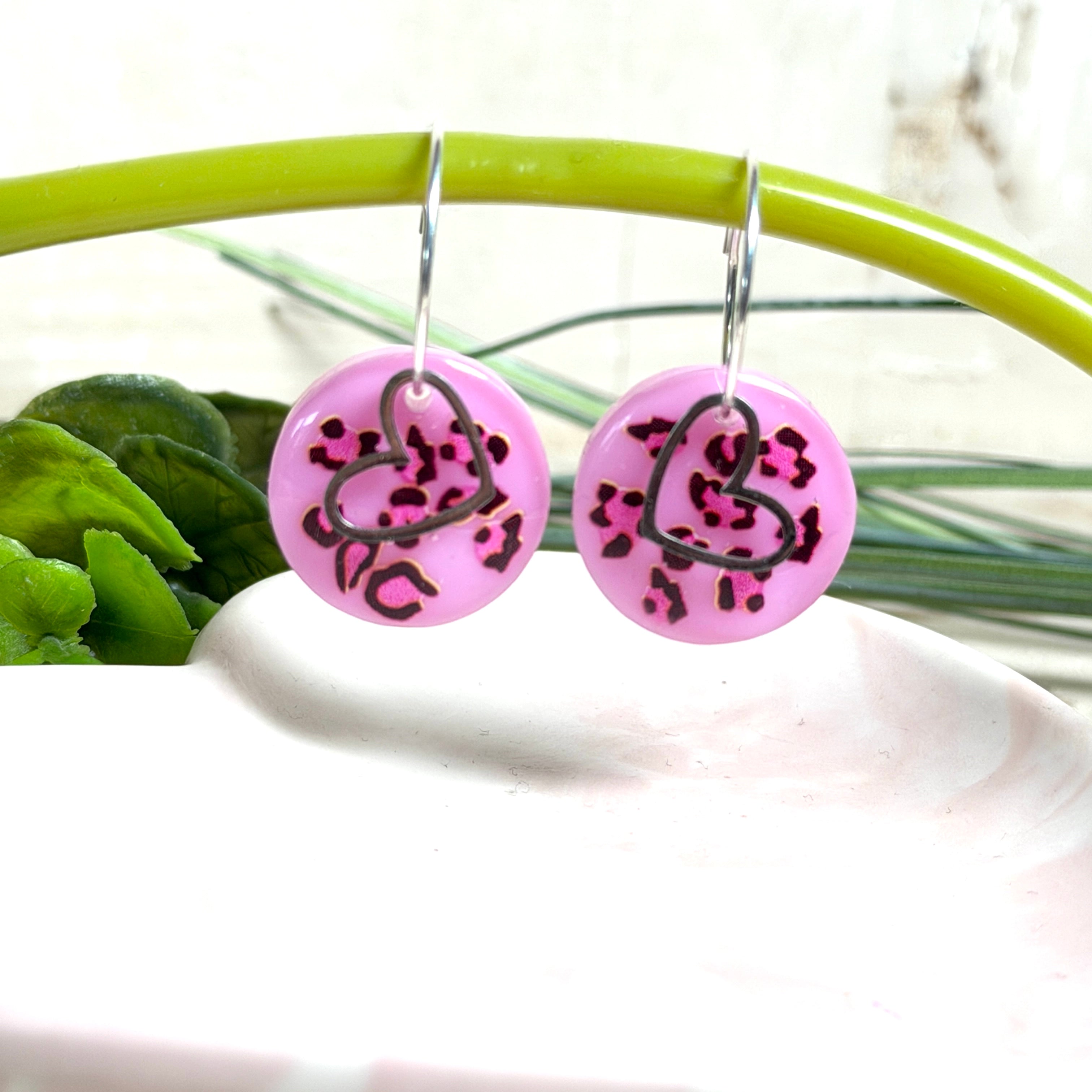 Handgemachte Leo-Creolen aus 925 Silber: Silber-Creolen 16 mm mit rosa Harz-Scheibe (2 cm) im Leoparden-Look und Edelstahl-Herzanhänger. Hängende Ohrringe in Animal-Print Stil, Gesamtlänge ca. 3,5 cm. Resin-Ohrringe für Alltag, Party oder Festival, femininer Statement-Schmuck in Rosa/Pink mit silberfarbenen Metallteilen. Einzeln gegossen, jedes Paar ein Unikat; leichte Abweichungen im Muster, Farbspiel und kleine Luftbläschen sind möglich und typisch für Handarbeit.