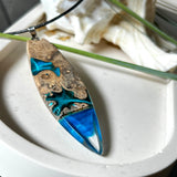 Handgefertigter Surfbrett-Anhänger aus Maserholz und transparentem Harz mit Farbverlauf in Blau und Weiß. Die natürliche Maserung des Holzes trifft auf ozeanartige Harzstrukturen. Größe ca. 6,7 x 2 cm, mit Edelstahlöse und Lederband inkl. Karabinerverschluss (45 cm + 5 cm Verlängerung). Jedes Stück ist ein Unikat – maritim, modern und mit viel Liebe gefertigt.
