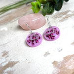 Handgemachte Leo-Creolen aus 925 Silber: Silber-Creolen 16 mm mit rosa Harz-Scheibe (2 cm) im Leoparden-Look und Edelstahl-Herzanhänger. Hängende Ohrringe in Animal-Print Stil, Gesamtlänge ca. 3,5 cm. Resin-Ohrringe für Alltag, Party oder Festival, femininer Statement-Schmuck in Rosa/Pink mit silberfarbenen Metallteilen. Einzeln gegossen, jedes Paar ein Unikat; leichte Abweichungen im Muster, Farbspiel und kleine Luftbläschen sind möglich und typisch für Handarbeit.