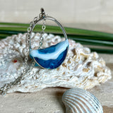 Ovale Halskette „Ocean Crest“ mit 3D-Welle: handgefertigter Harz-Anhänger in Silber-Legierung, Farbverlauf von Tiefblau zu Türkis mit weißer Schaumkrone. Größe ca. 3,9 × 2,3 cm, an einer ca. 56 cm langen versilberten Kette. Glänzende Oberfläche, maritimer Look, Unikat-Handarbeit.