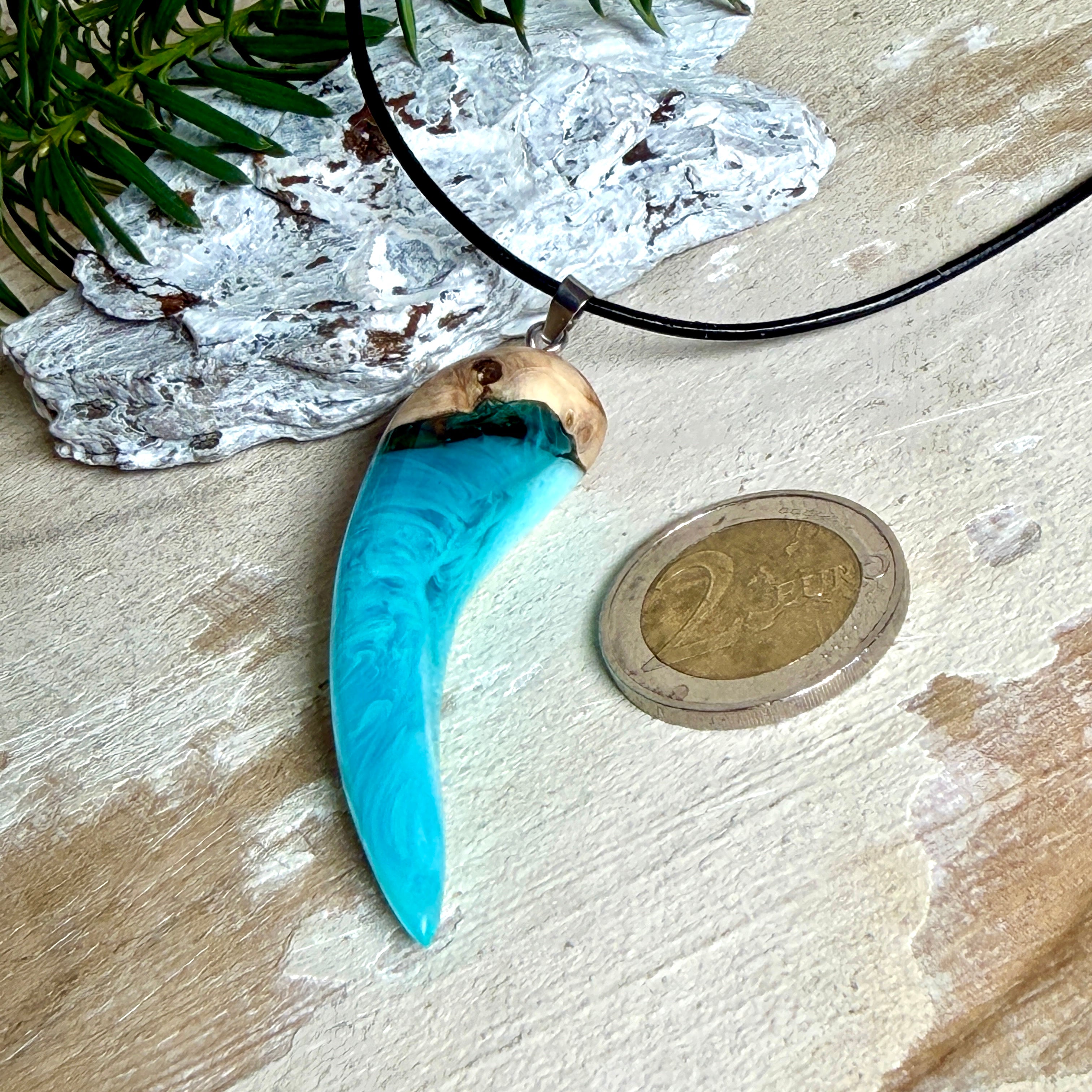 Handgefertigter Anhänger aus Edelholz und transparent-türkisblauem und weißen Epoxidharz, glatt poliert. Größe ca. 6,5 × 2,0 cm. Mit Edelstahlöse an schwarzer Lederkette (45 cm + 5 cm Edelstahl-Verlängerung, Karabiner). Moderner, unisex tragbarer Schmuck mit natürlicher Holzmaserung; kleine Lufteinschlüsse sind charakteristisch.