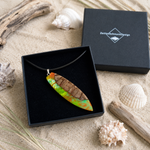 Tropical Glow Surfbrett Anhänger aus Rebholz und fluoreszierendem Epoxidharz in Grün, Orange und Türkis, handgefertigte Lederkette in schwarzer Schmuckbox von ZeitlosSchmuckDesign, maritimer Unisex Schmuck mit UV-Schwarzlicht-Effekt.
