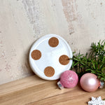 Runder Teelichthalter aus klarem Epoxidharz, Durchmesser ca. 7 cm, Höhe ca. 4 cm. Im Harz sind rosa Weihnachtskugeln, ein Stern, eine Schneeflocke, ein Tannenbaum, künstliche Tannennadeln und feiner Glitzer eingegossen. Vertiefung für ein Teelicht in der Mitte, Unterseite mit vier Korkpads als Möbelschoner. Fotografiert auf Holz mit Tannenzweig und rosa Kugeln als weihnachtliche Dekoration