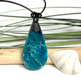 Tropfen Anhänger aus dunklem Maserholz und Epoxidharz in Türkis Blau mit weißer Wellenstruktur am schwarzen Lederband, maritimer Holz Harz Naturschmuck