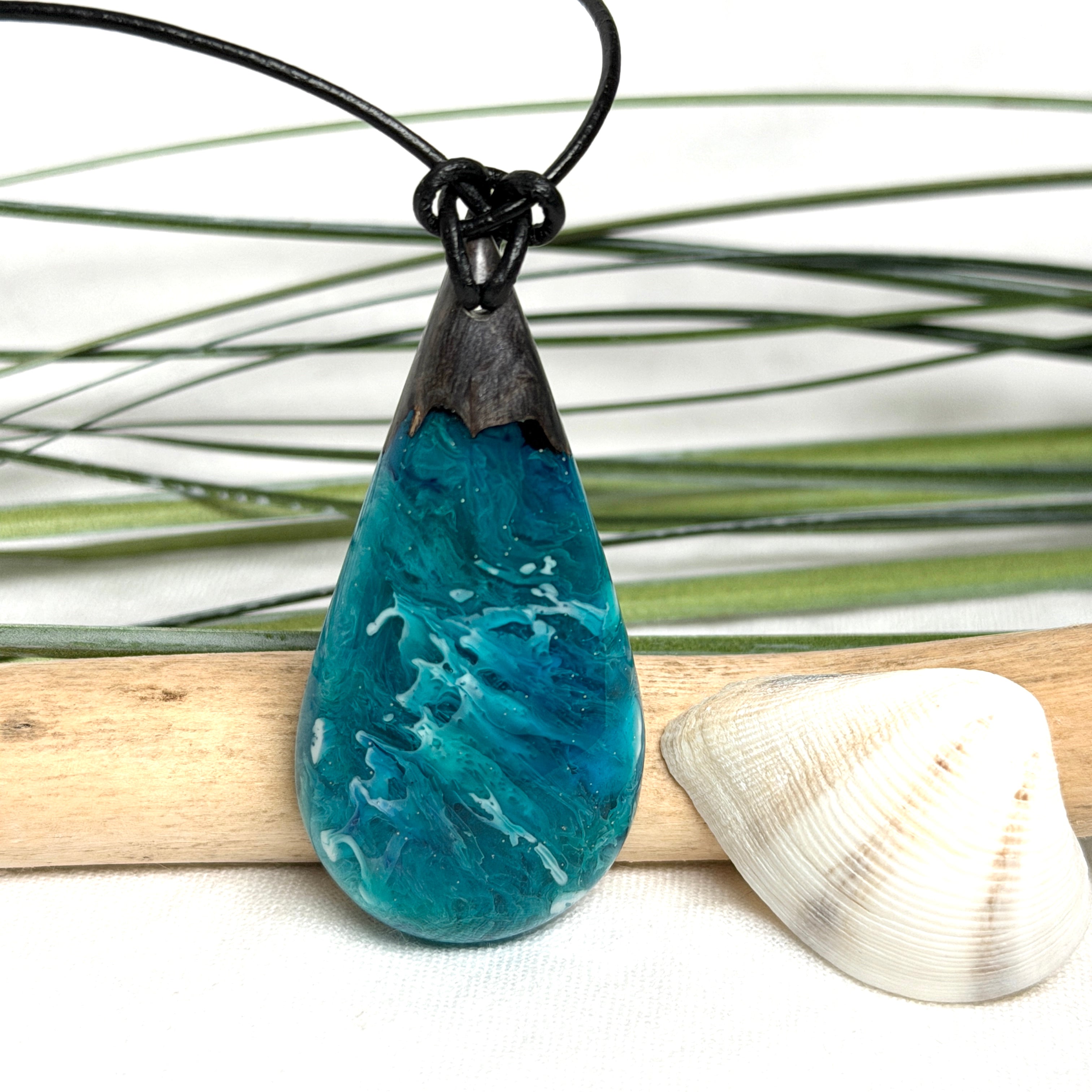 Tropfen Anhänger aus dunklem Maserholz und Epoxidharz in Türkis Blau mit weißer Wellenstruktur am schwarzen Lederband, maritimer Holz Harz Naturschmuck
