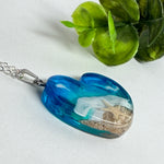 Ein herzförmiger Anhänger mit einer ganzen Ozeanwelt darin: Welle, Sand und Seestern in leuchtendem Blau und Türkis – handgegossen, einzigartig, unvergesslich. Mit versilberter Kette (46 cm) und Edelstahl-Karabiner.