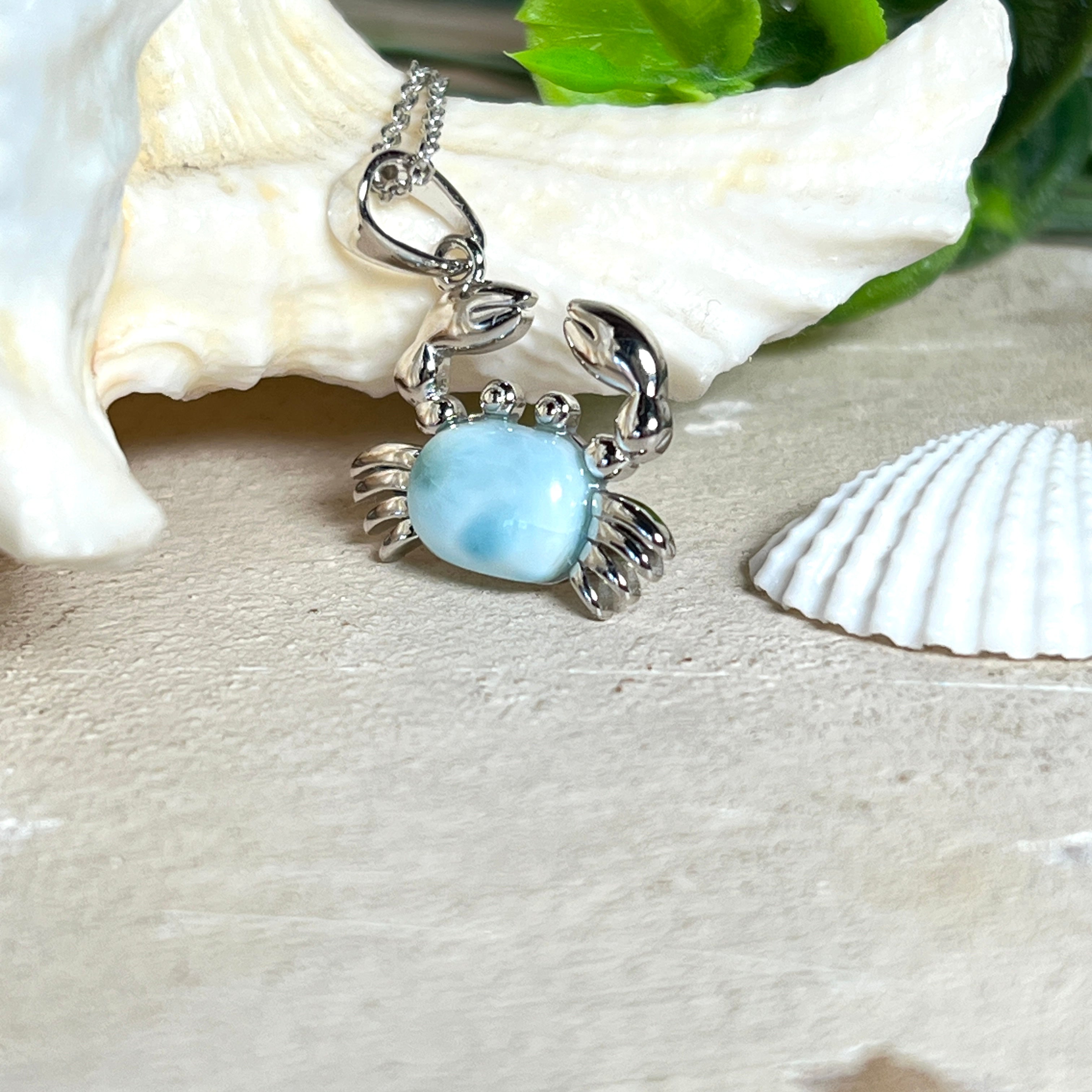 Krabben-Anhänger „Crab of Light“ aus rhodiniertem 925 Sterling Silber mit seltenem Larimar Edelstein aus der Dominikanischen Republik. Der Anhänger (28 × 18 mm) wird mit einer feinen 45 cm langen Silberkette geliefert. Symbol für Schutz, Intuition und die Kraft des Meeres – jedes Schmuckstück ein Unikat durch das natürliche Farbspiel des Larimars.