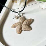 Handgefertigter Anhänger in Seesternform aus echtem Meersand und transparentem Harz. Verziert mit einer natürlichen Süßwasserperle. Edelstahlöse, Lederkette mit Karabinerverschluss (45 cm + 5 cm Verlängerung). Maritimer Schmuck im Unikatcharakter – inspiriert vom Meer und handgefertigt mit Liebe zum Detail. Perfektes Geschenk für Strandliebhaber.