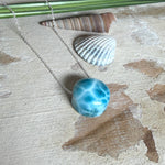 Feine Kette mit rundem Larimar-Cabochon in AA-Qualität. Der ca. 20 mm große Stein zeigt ein intensives Blau mit hellen, netzartigen Zeichnungen und ist mittig mit einer 2,5 mm Bohrung versehen, durch die eine zarte 925 Silberkette (45 cm, ca. 1 mm stark) geführt wird. 