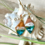 Handgefertigte Ohrringe „Ocean Diamond“ aus Olivenholz und Epoxidharz in Diamantform. Türkis-, Blau- und Weißtöne bilden ein wellenartiges Design, inspiriert vom Meer. Jeder Ohrring ist ein Unikat mit individueller Maserung. Vergoldete, nickelfreie und bleifreie Anhängerschlaufe, 925 Sterling Silber Ohrhaken. Maritimer Schmuck für Meerliebhaber und besondere Anlässe.