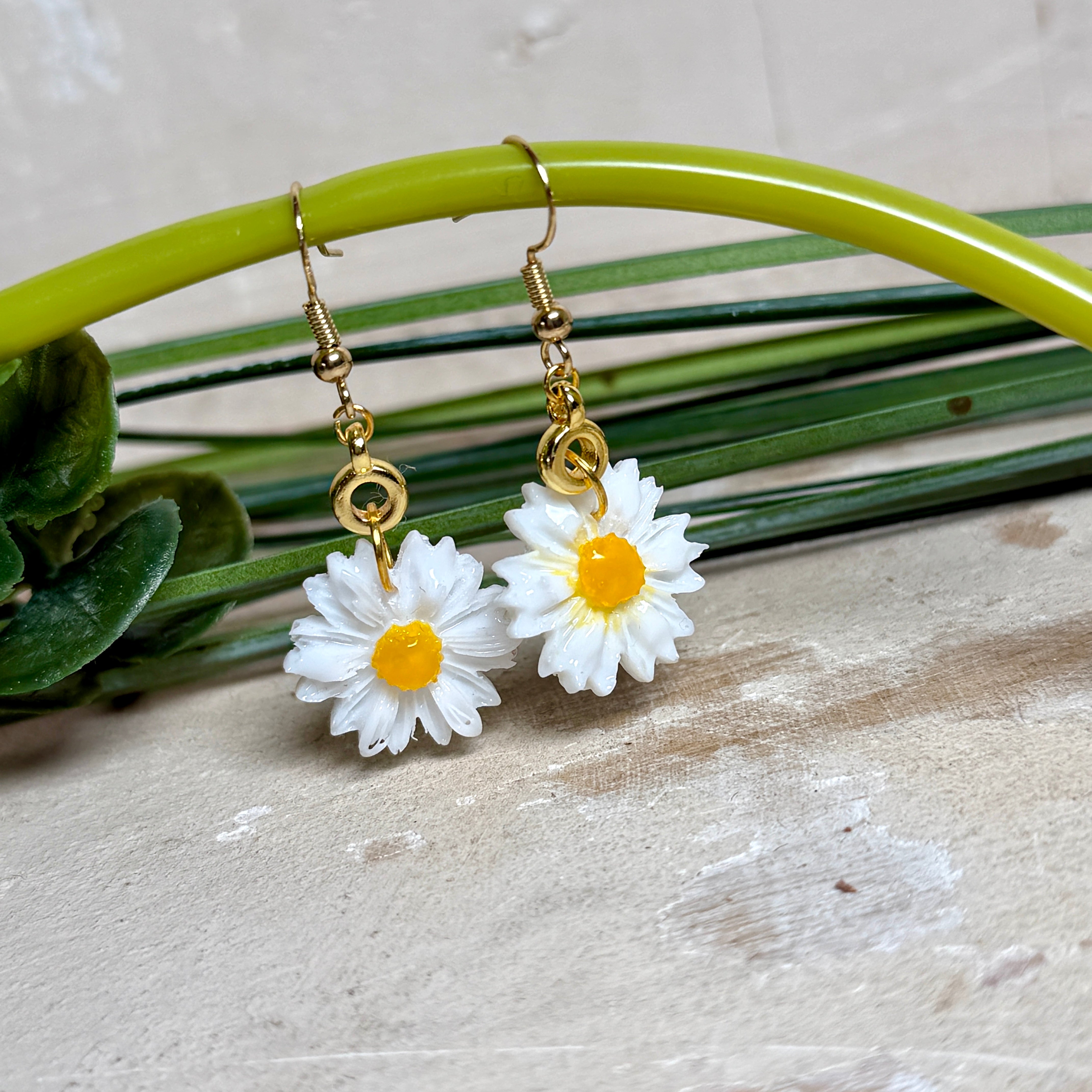 Handgefertigte Gänseblümchen-Ohrringe aus Harz mit 925 vergoldeten Ohrhaken, weiße Blüte mit gelbem Zentrum, goldfarbene Details, Länge ca. 4,5 cm.