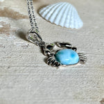 Krabben-Anhänger „Crab of Light“ aus rhodiniertem 925 Sterling Silber mit seltenem Larimar Edelstein aus der Dominikanischen Republik. Der Anhänger (28 × 18 mm) wird mit einer feinen 45 cm langen Silberkette geliefert. Symbol für Schutz, Intuition und die Kraft des Meeres – jedes Schmuckstück ein Unikat durch das natürliche Farbspiel des Larimars.