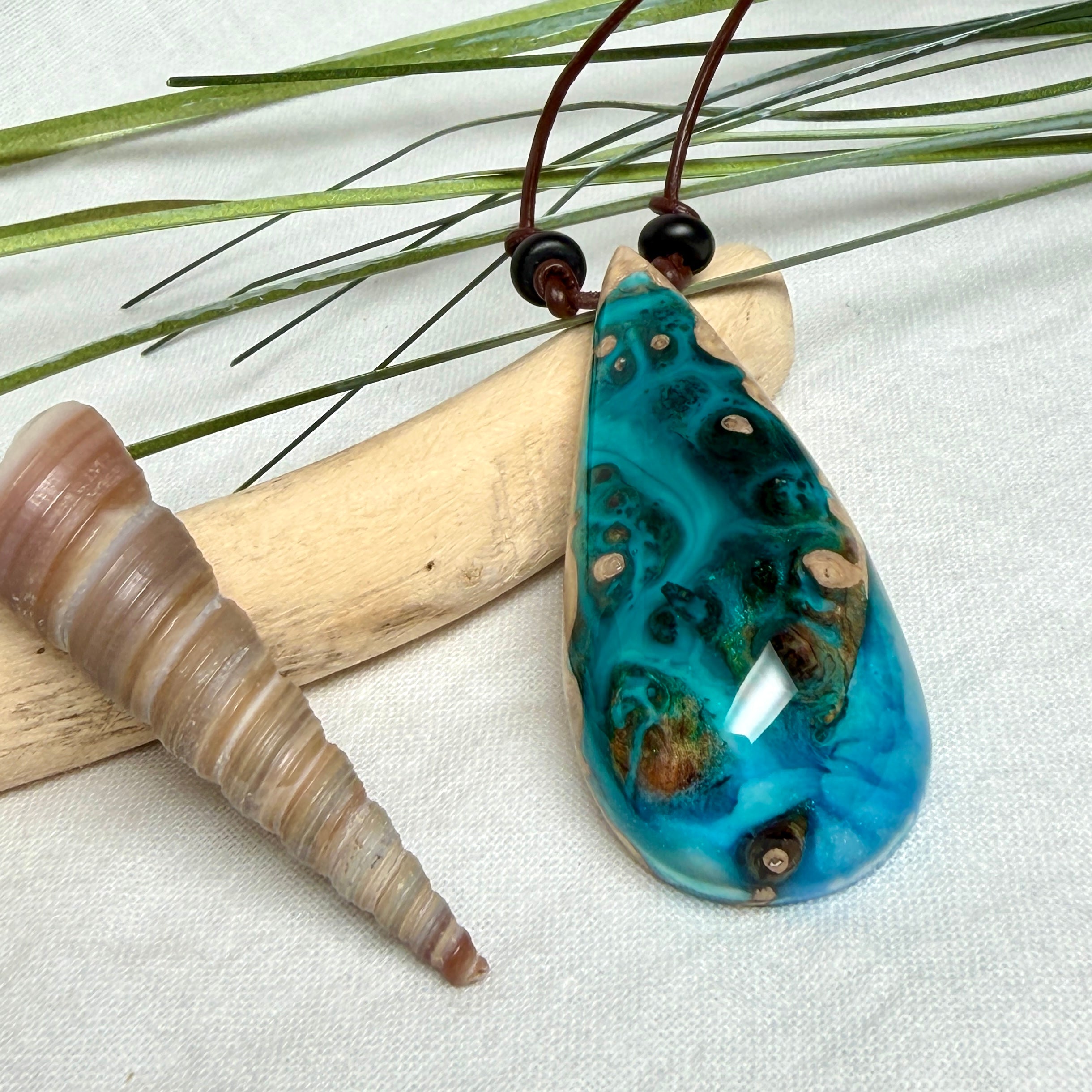 Holz-Harz-Anhänger aus Maserholz mit türkis-blauem Epoxidharz in Tropfenform am verstellbaren Lederband mit Onyxperlen, handgemachter maritimer Naturschmuck