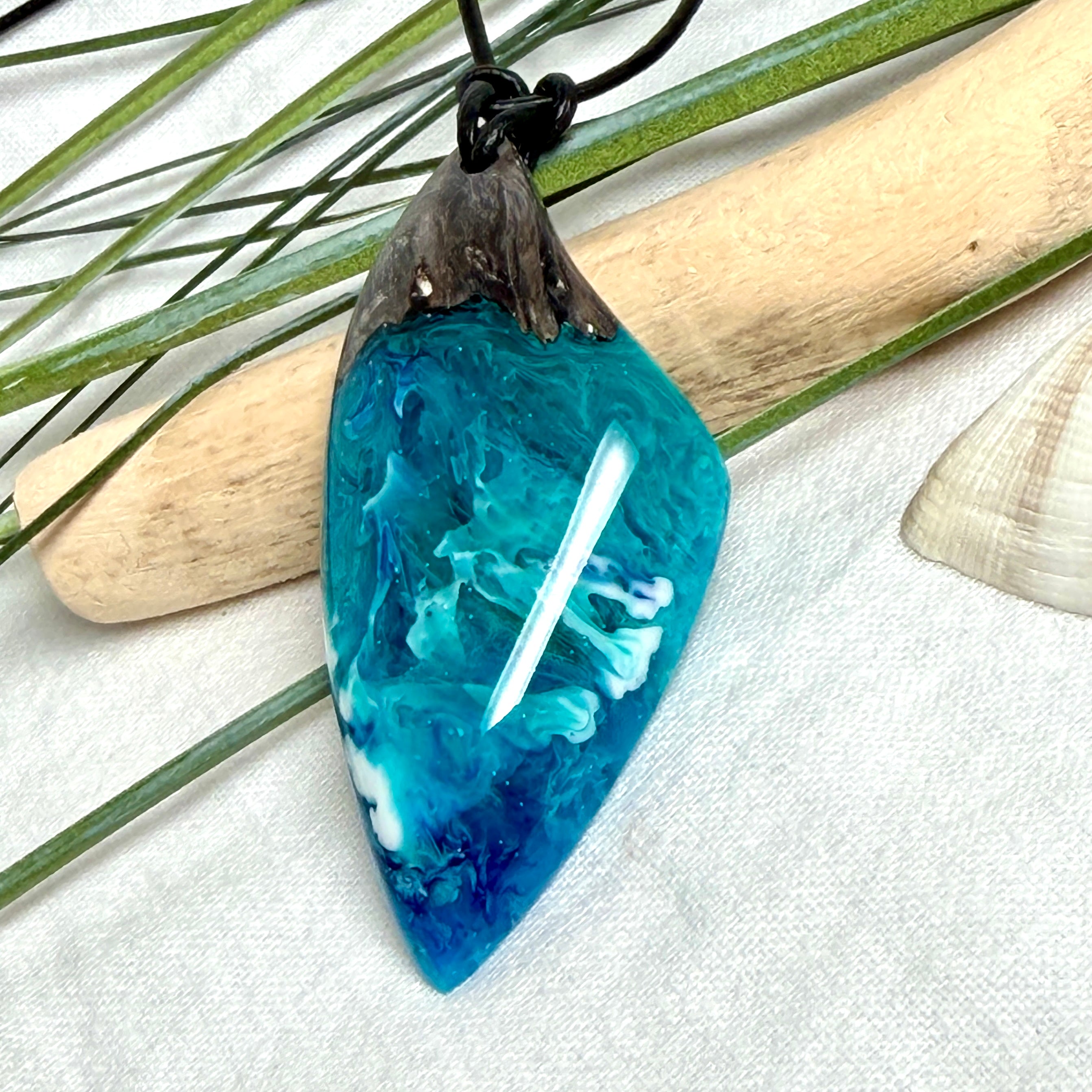 Anhänger aus dunklem Maserholz und Epoxidharz in Blau Türkis mit weißer Wellenstruktur am schwarzen Lederband, maritimer Holz Harz Naturschmuck unisex