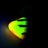 Herz-Anhänger aus Pinienzapfen & Harz, fluoreszierend bei Schwarzlicht. Farben Gelb-Orange-Weiß, Größe 4,2 × 3,8 cm. Lederband verstellbar.