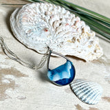 „Lagunenlicht“ – Tropfenanhänger mit handmodellierter 3D-Welle und feinem Glitzereffekt. Klarer Harzlook in Blau/Türkis, gefasst in Silber-Legierung. Größe ca. 3,5 × 2 cm. Geliefert an einer versilberten Kette (ca. 56 cm). Hochglänzend , maritimer Unikatcharakter.