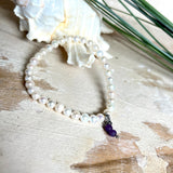 Handgefertigtes Armband „Sea Harmony“ mit schimmernden Süßwasserperlen (Ø ca. 6–7 mm), jede Perle ein Unikat. Auf elastischem Band gefädelt, mit einem filigranen Charmanhänger aus  Amethyst-Perlen, befestigt an einem robusten Edelstahl-Karabiner. Ein Schmuckstück voller Eleganz, maritimer Harmonie und symbolischer Tiefe – ideal als Geschenk oder als stilvolles Accessoire.
