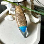 Handgefertigter Surfbrett-Anhänger aus Maserholz und transparentem Harz mit Farbverlauf in Blau und Weiß. Die natürliche Maserung des Holzes trifft auf ozeanartige Harzstrukturen. Größe ca. 6,7 x 2 cm, mit Edelstahlöse und Lederband inkl. Karabinerverschluss (45 cm + 5 cm Verlängerung). Jedes Stück ist ein Unikat – maritim, modern und mit viel Liebe gefertigt.