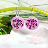 Handgemachte Leo-Creolen aus 925 Silber: Silber-Creolen 16 mm mit rosa Harz-Scheibe (2 cm) im Leoparden-Look und Edelstahl-Herzanhänger. Hängende Ohrringe in Animal-Print Stil, Gesamtlänge ca. 3,5 cm. Resin-Ohrringe für Alltag, Party oder Festival, femininer Statement-Schmuck in Rosa/Pink mit silberfarbenen Metallteilen. Einzeln gegossen, jedes Paar ein Unikat; leichte Abweichungen im Muster, Farbspiel und kleine Luftbläschen sind möglich und typisch für Handarbeit.