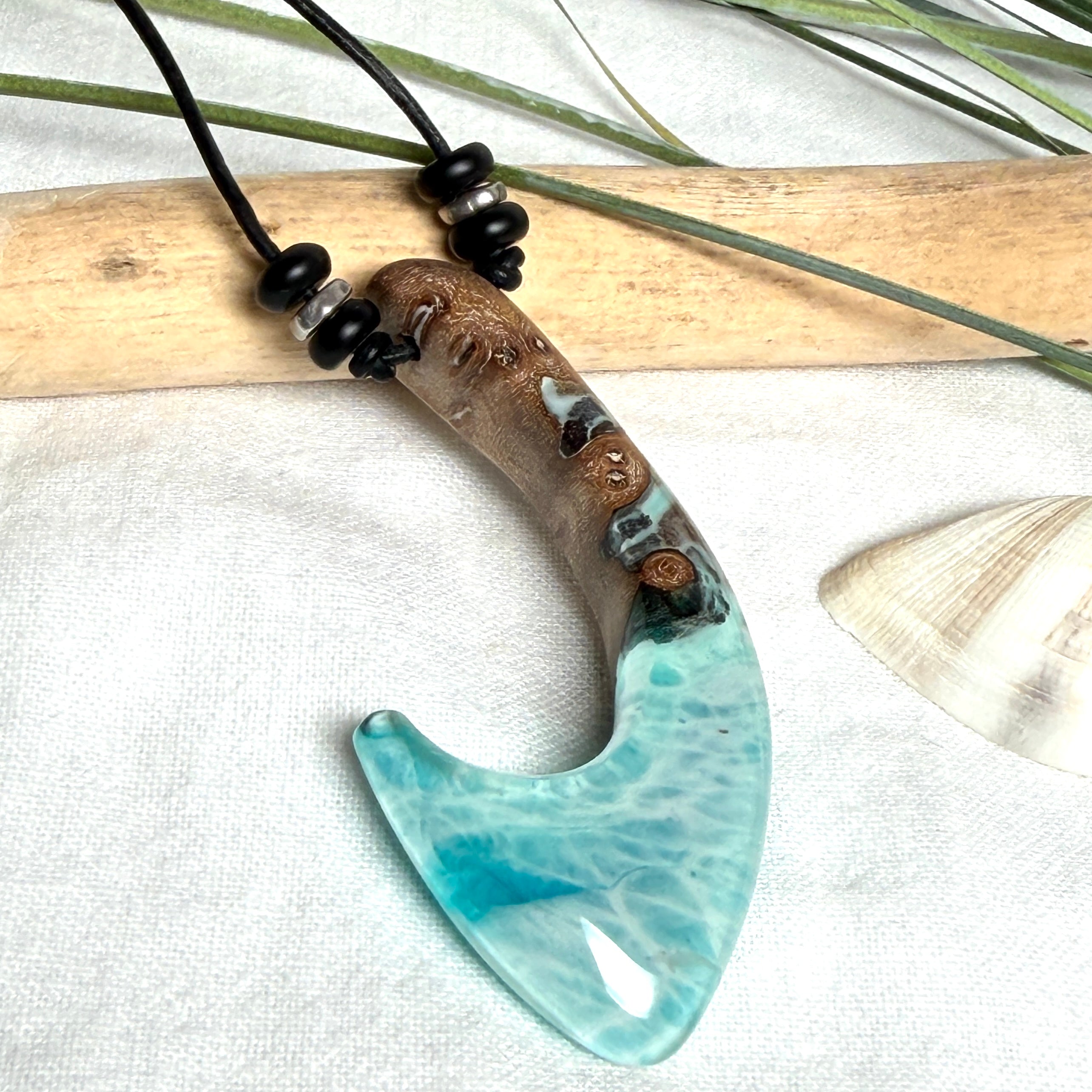 Angelhaken Anhänger aus braunem Maserholz und türkis hellblauem Epoxidharz am schwarzen Lederband mit Onyxperlen, Hei Matau Naturschmuck im Māori Stil