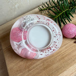 Rosa Teelichthalter aus klarem Epoxidharz, ca. 8 × 6,5 cm, Höhe ca. 4 cm. Im Harz sind kleine rosa Weihnachtskugeln, ein Stern, eine Schneeflocke und rosa Granulat eingegossen. Ovaler Halter für ein Teelicht, Unterseite mit vier runden Korkpads als Möbelschoner. Fotografiert auf Holz mit Tannenzweig und rosa Kugeln als weihnachtlicher Dekohintergrund.