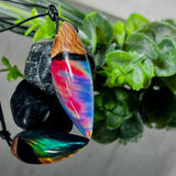 Der handgefertigte Anhänger „Celestial Flame“ kombiniert warmes Olivenholz mit glasklarem Harz und irisierendem Opal. Das einzigartige Farbspiel erinnert an Polarlichter und verleiht dem Schmuckstück eine mystische Tiefe. Die Oberfläche ist glatt poliert, der Anhänger wird an einem verstellbaren Lederband getragen – ein ausdrucksstarkes Unikat für alle, die Naturmaterialien und kreative Farben lieben.