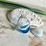 Ovale Halskette „Ocean Crest“ mit 3D-Welle: handgefertigter Harz-Anhänger in Silber-Legierung, Farbverlauf von Tiefblau zu Türkis mit weißer Schaumkrone. Größe ca. 3,9 × 2,3 cm, an einer ca. 56 cm langen versilberten Kette. Glänzende Oberfläche, maritimer Look, Unikat-Handarbeit.