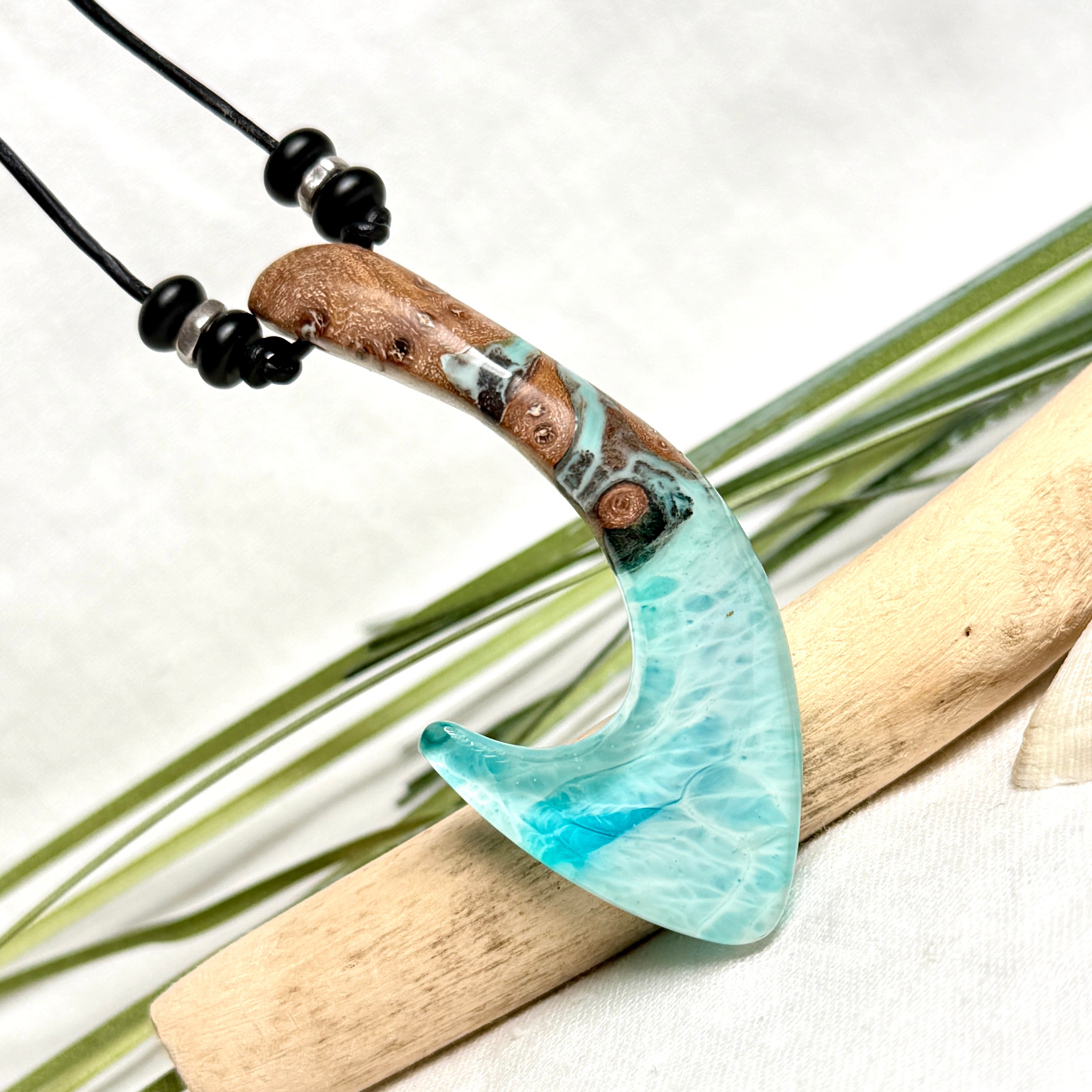 Angelhaken Anhänger aus braunem Maserholz und türkis hellblauem Epoxidharz am schwarzen Lederband mit Onyxperlen, Hei Matau Naturschmuck im Māori Stil