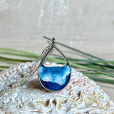 „Lagunenlicht“ – Tropfenanhänger mit handmodellierter 3D-Welle und feinem Glitzereffekt. Klarer Harzlook in Blau/Türkis, gefasst in Silber-Legierung. Größe ca. 3,5 × 2 cm. Geliefert an einer versilberten Kette (ca. 56 cm). Hochglänzend , maritimer Unikatcharakter.