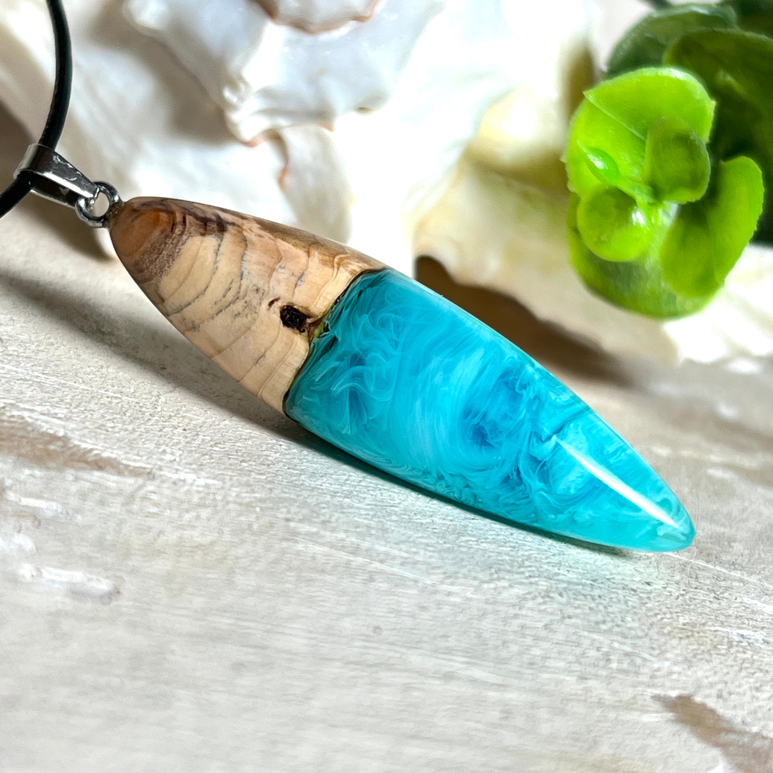 Anhänger aus Eibenholz und Epoxidharz in Blau-Türkis, Weiß und Transparent. Größe ca. 5,8 × 2 cm, Edelstahlöse, Lederkette 45+5 cm. Handgefertigtes Unikat inspiriert vom Ozean.