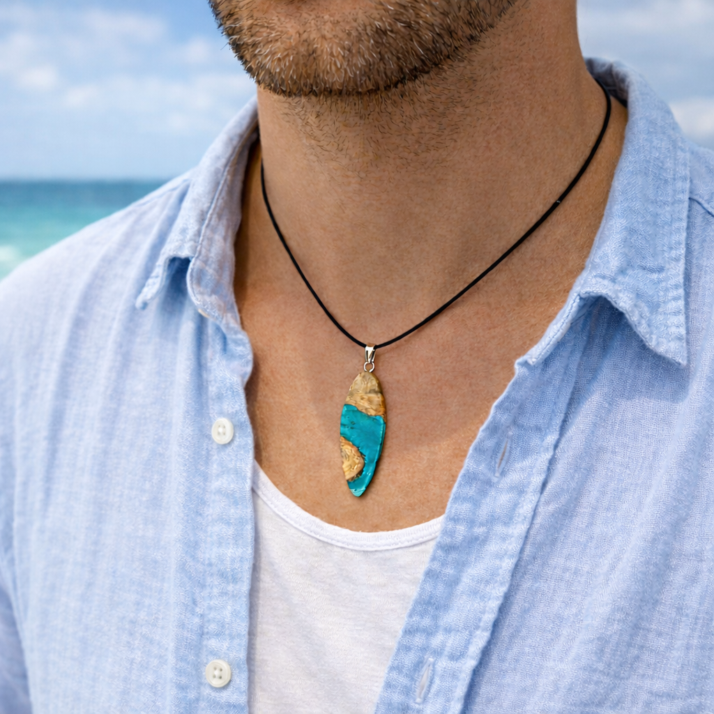 Handgefertigte Surfbrett Kette aus Maserholz und türkisfarbenem Resin mit Edelstahl Anhängerschlaufe an schwarzer Lederkette mit Karabiner und Verlängerung. Filigraner Ocean Anhänger inspiriert von Meer und Wellen, natürlicher Unikat Schmuck für Damen und Herren.