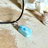 Larimar Freeform Anhänger mit rhodinierter Silberöse an schwarzer Lederkette. Der seltene, kostbare Larimar („Atlantisstein“) zeigt ein lebendiges Muster aus Türkis- und Weißtönen. Beidseitig tragbar, Steingröße ca. 2 x 1 cm, Lederkette 45 cm mit Edelstahl-Karabiner und 5 cm Verlängerung. Natürlicher, maritimer Unikatschmuck.