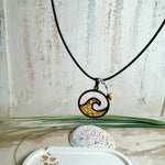 “Runder Wellenanhänger aus Edelstahl mit Bernstein-Harz-Inlay, Jaspisperle & facettiertem Bergkristall an schwarzer Lederkette (45 cm + 5 cm).”