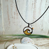 “Runder Wellenanhänger aus Edelstahl mit Bernstein-Harz-Inlay, Jaspisperle & facettiertem Bergkristall an schwarzer Lederkette (45 cm + 5 cm).”