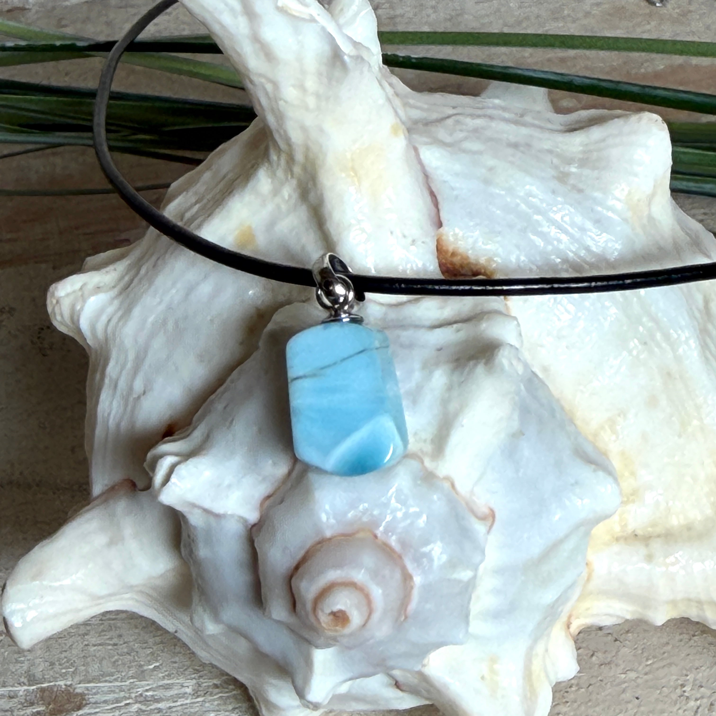 Larimar Freeform Anhänger mit rhodinierter Silberöse an schwarzer Lederkette. Der seltene, kostbare Larimar („Atlantisstein“) zeigt ein lebendiges Muster aus Türkis- und Weißtönen. Beidseitig tragbar, Steingröße ca. 2 x 1 cm, Lederkette 45 cm mit Edelstahl-Karabiner und 5 cm Verlängerung. Natürlicher, maritimer Unikatschmuck.