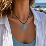 KI-Tragebild TURQUOISE BAY – handgefertigte Seeglas Halskette mit türkisem Donut-Anhänger, Sonnen-Charm aus 304 Edelstahl und schwarzer Lederschnur, maritimer Boho Sommerschmuck für Frauen.