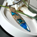 Handgefertigter Surfbrett-Anhänger aus Maserholz und transparentem Harz mit Farbverlauf in Blau und Weiß. Die natürliche Maserung des Holzes trifft auf ozeanartige Harzstrukturen. Größe ca. 6,7 x 2 cm, mit Edelstahlöse und Lederband inkl. Karabinerverschluss (45 cm + 5 cm Verlängerung). Jedes Stück ist ein Unikat – maritim, modern und mit viel Liebe gefertigt.